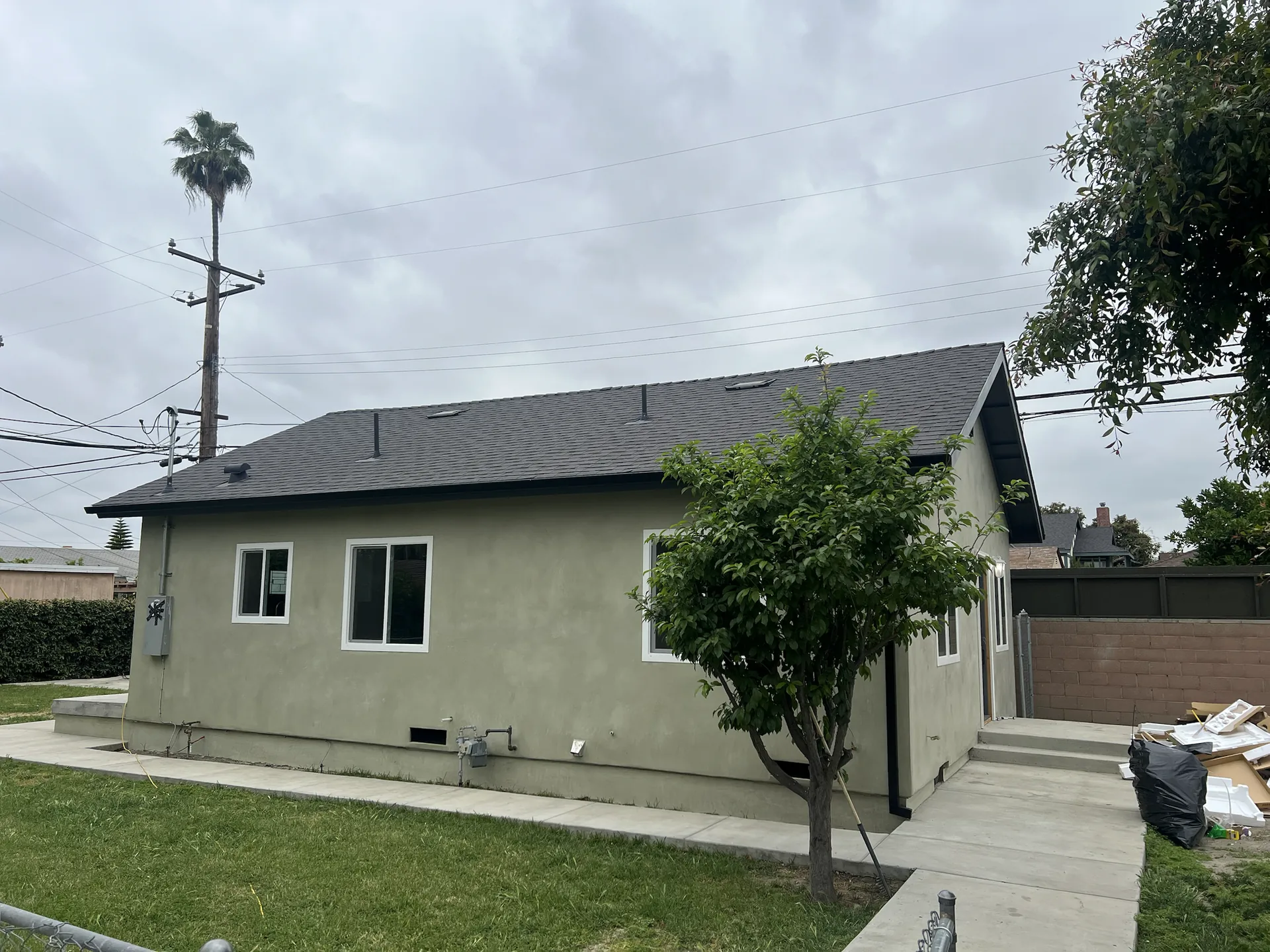 Renovated Downey home exterior with new light-gray stucco, white windows, and shingle roof