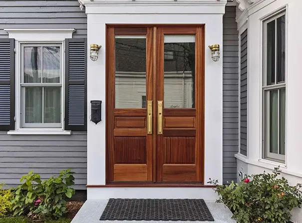 Wood double entry doors installed on a gray and white home